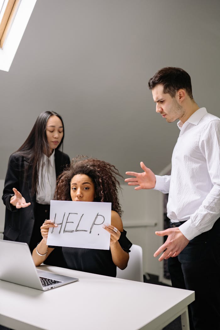 our-services-3 Woman holding HELP sign surrounded by colleagues in a tense office situation.